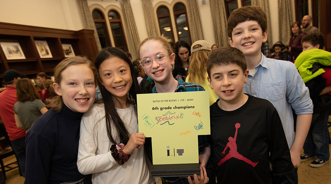 A group of children smile around a certificate of achievement at a past Battle of the Books